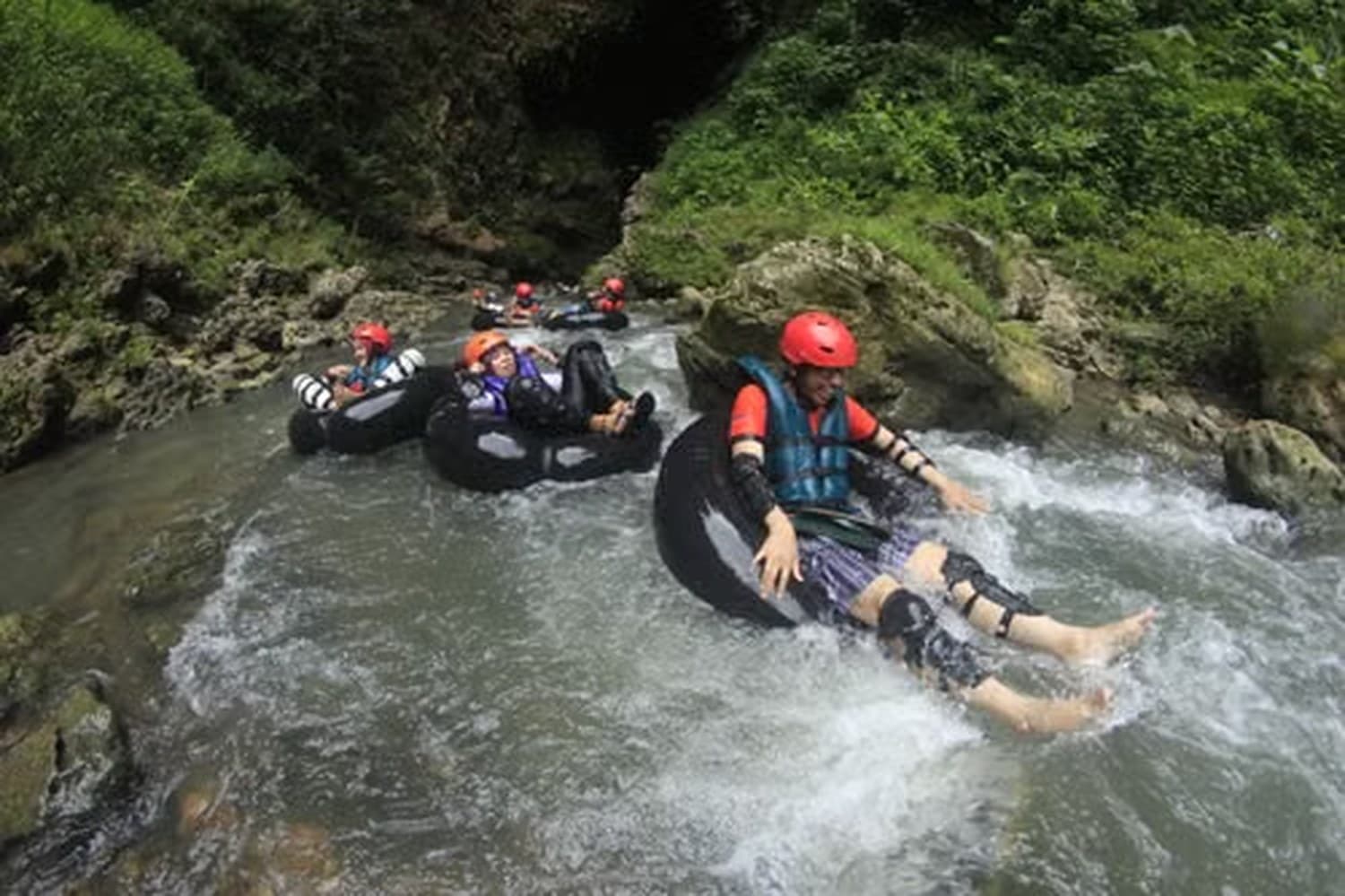 Guests in life jackets sitting on tubes in the upper Wos River canyon near Ubud